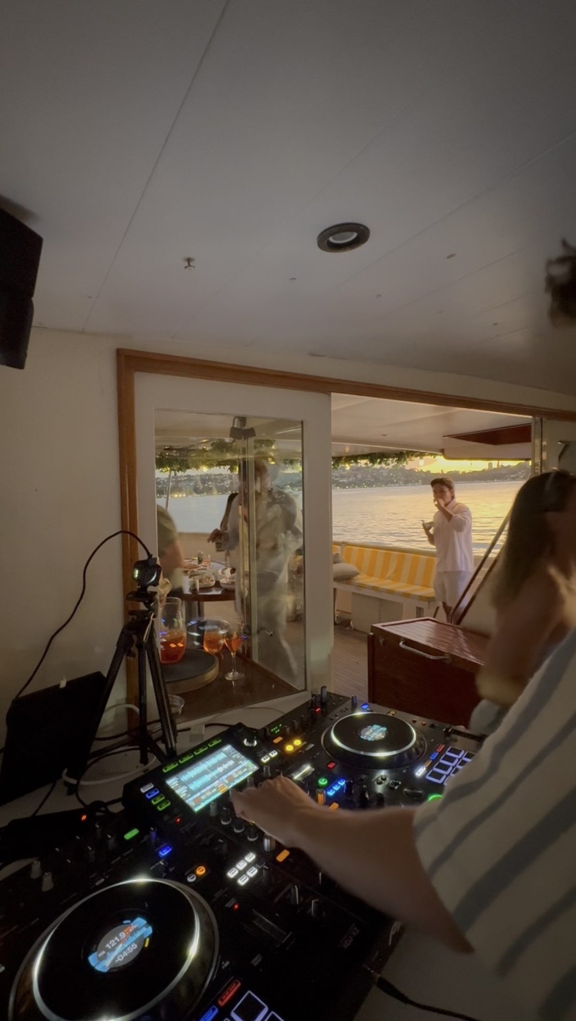 DJing on a harbour at sunset with golden light through the glass